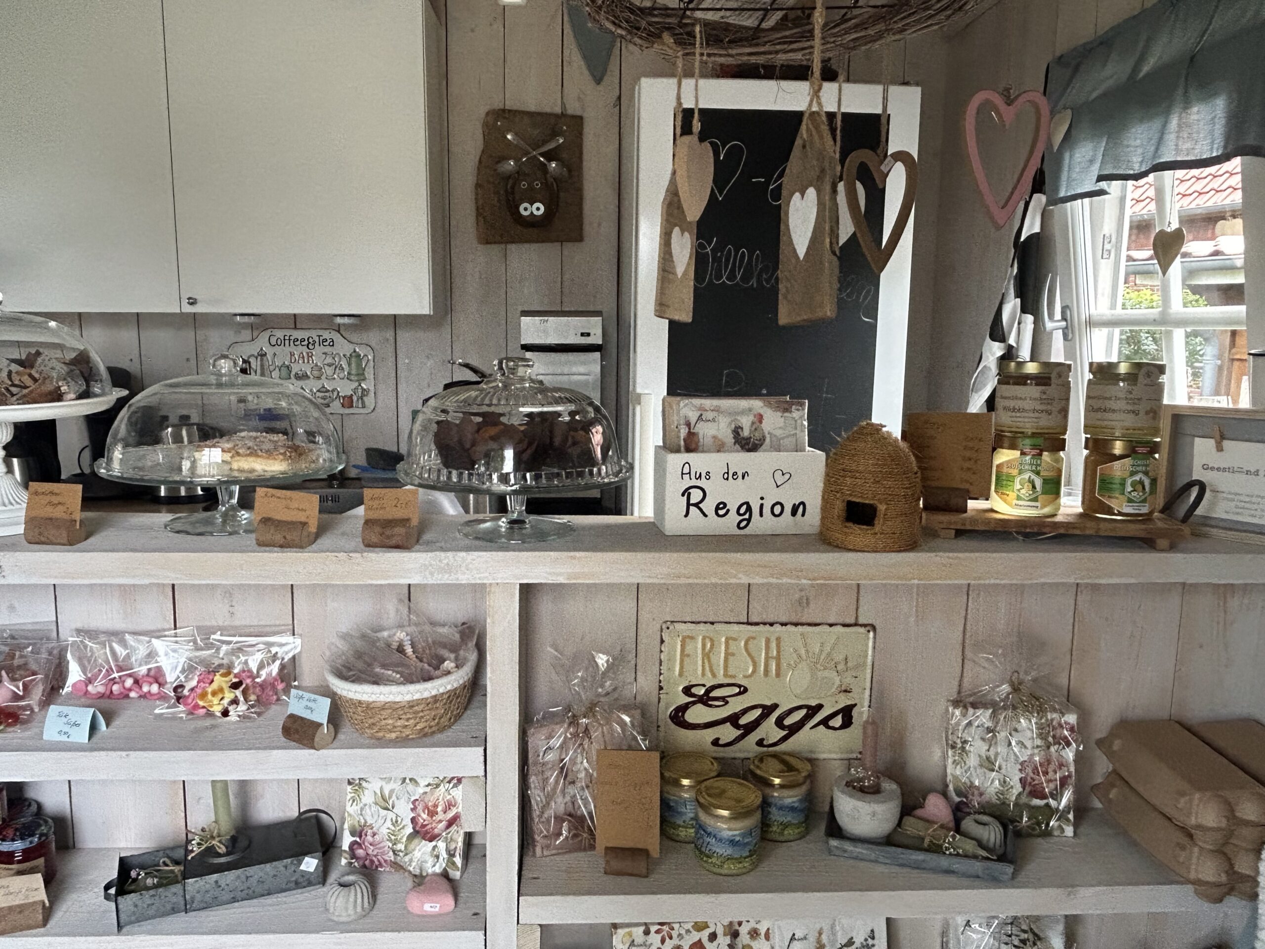 Verkaufstheke mit Honig, Kuchen und Dekoration in einem Melkhus