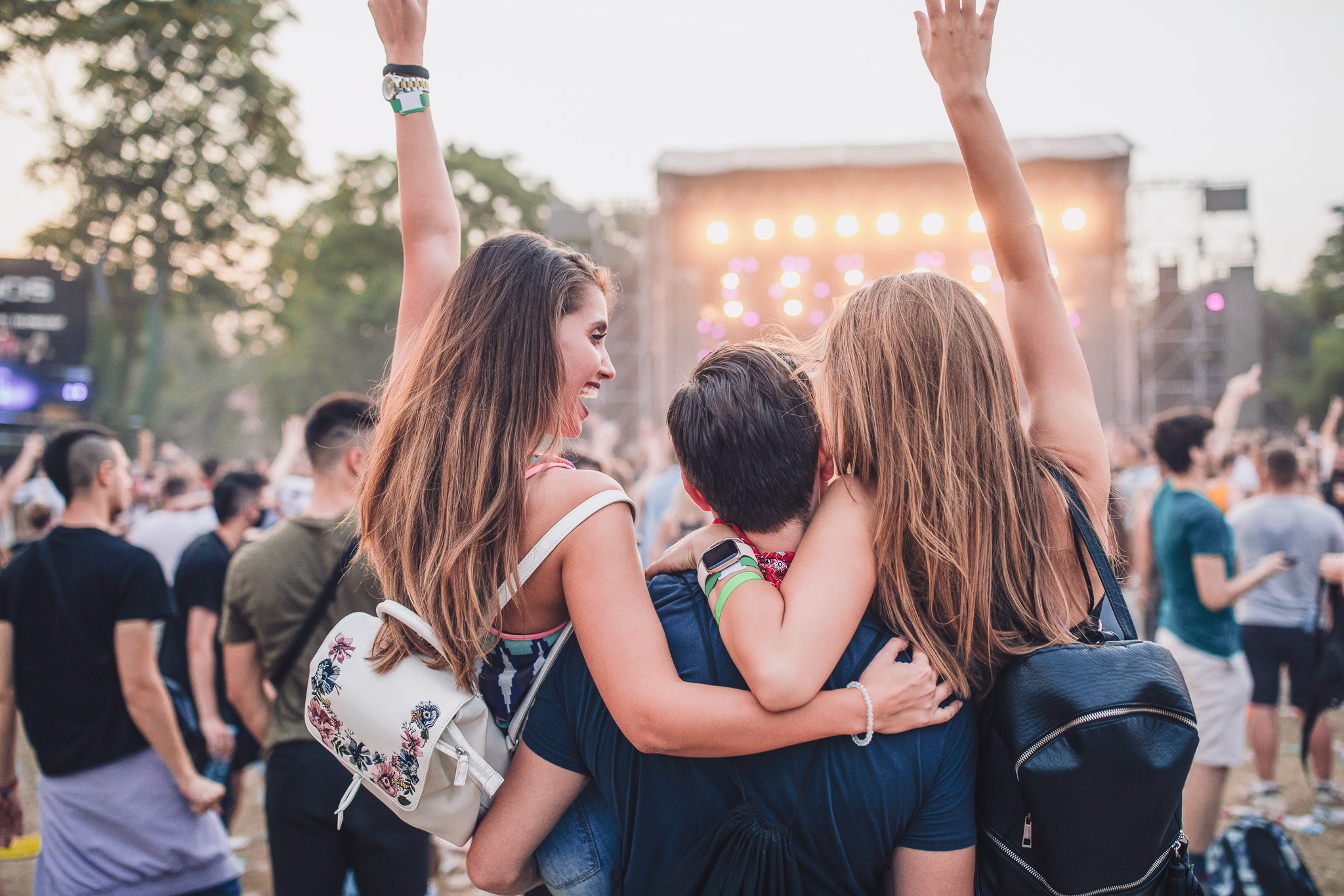 Teenager heben die Hände auf einem Open Air Konzert im Urlaub