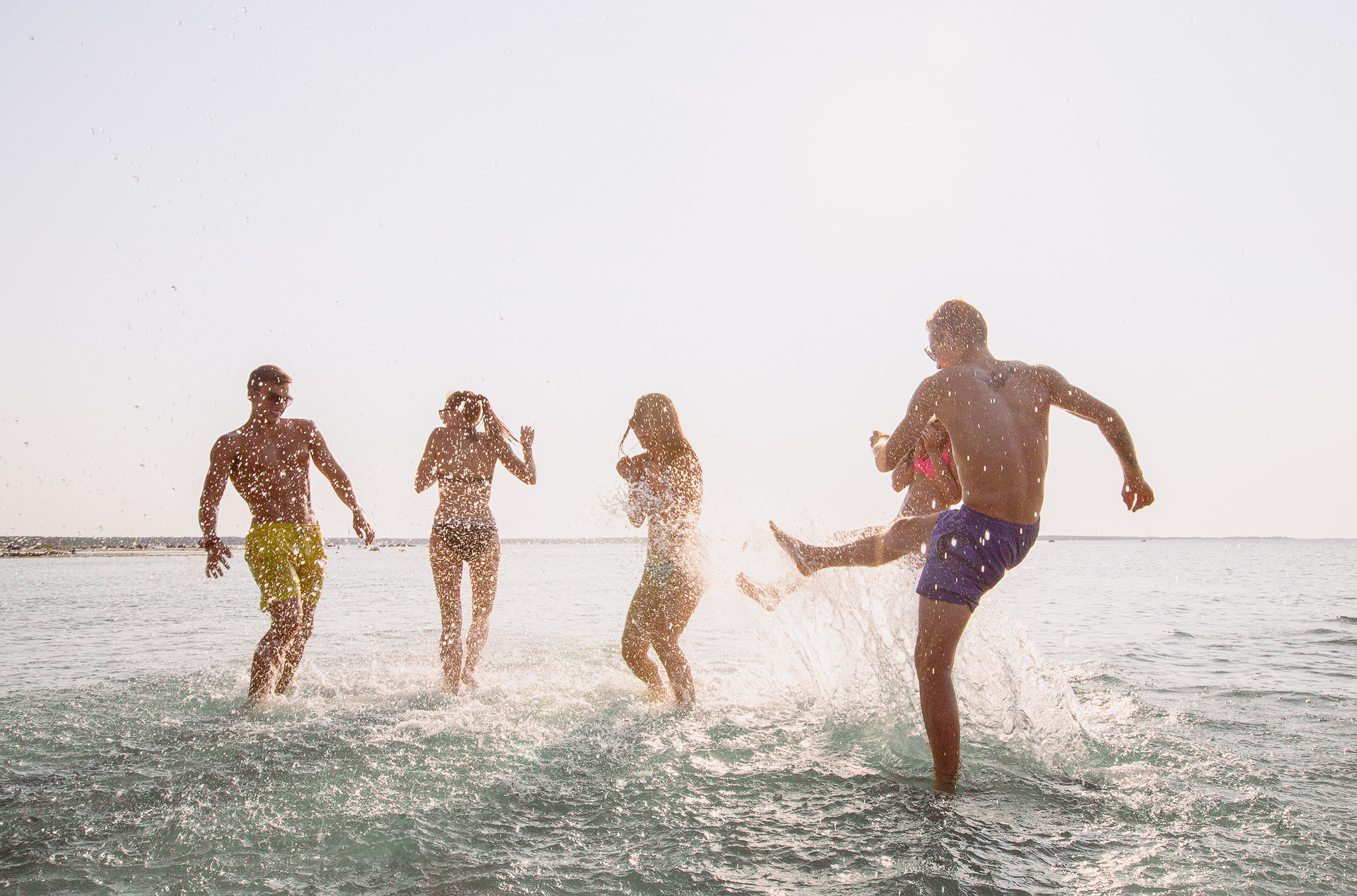 Familie mit Kindern und Teenagern spielt im flachen Wasser am Strand