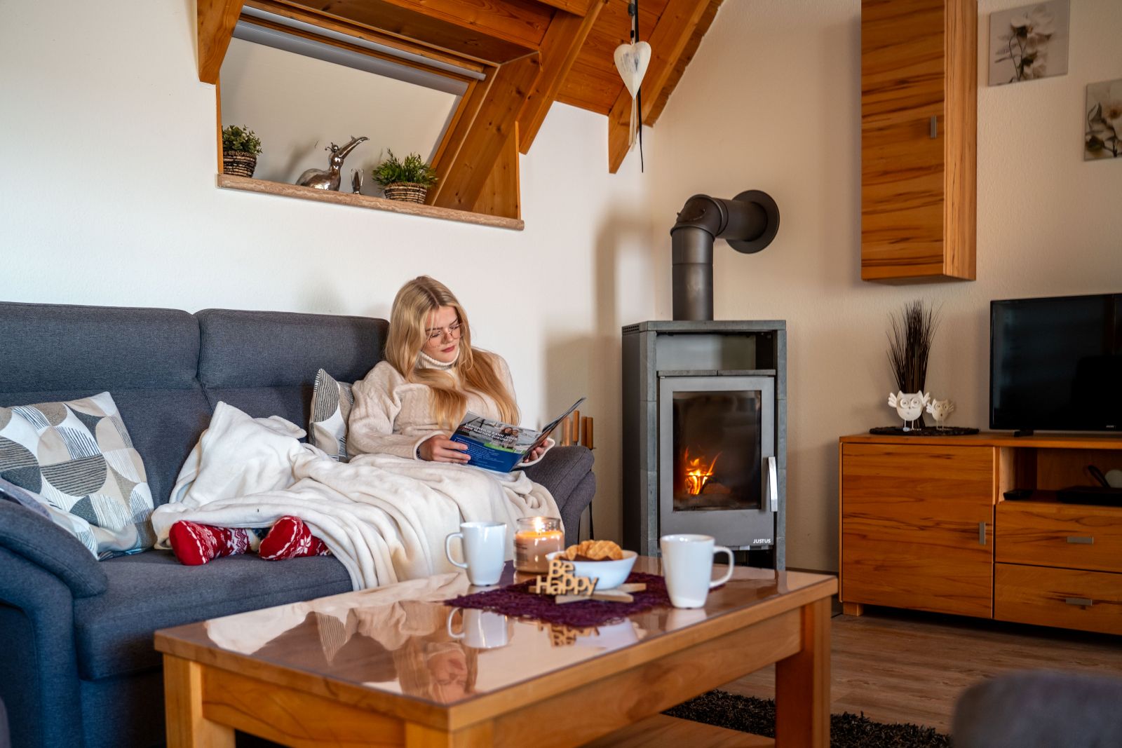 Junge Frau am Kaminofen im Ferienhaus in Dorum-Neufeld